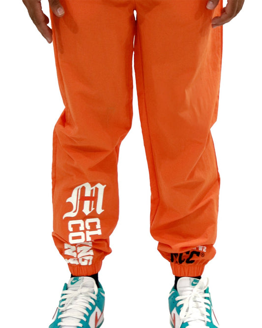 Orange nylon pants with Miami Clothing Co. logo and multi-graphic design, featuring elastic waistband and front welt pockets.